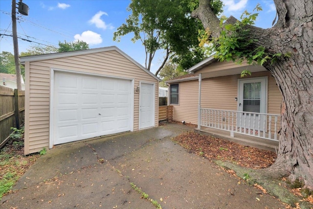 detached garage featuring asphalt driveway and fence