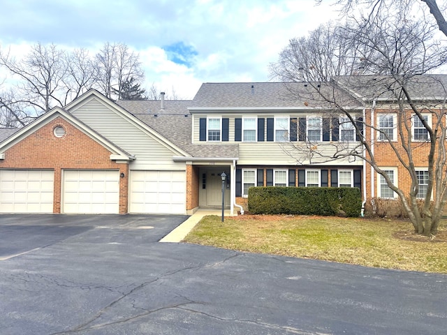 1510 Seville Ct Unit A1, Wheeling, IL 60090 - townhome / multi-family property featuring driveway, brick siding, a garage, a shingled roof, and a front yard