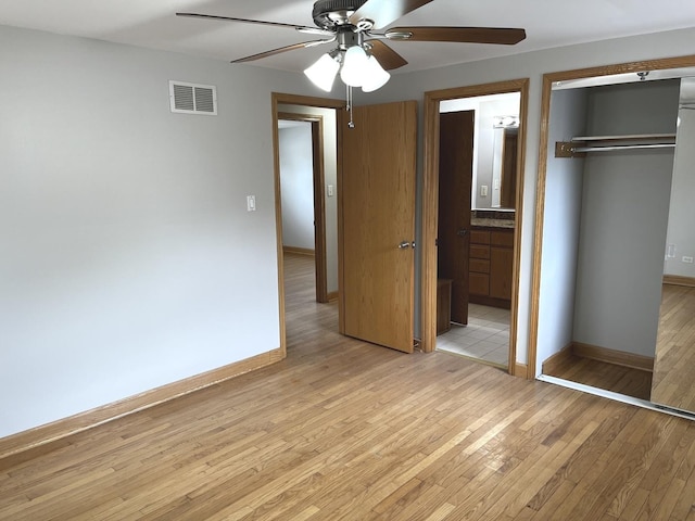 unfurnished bedroom with light wood-style flooring, a closet, baseboards, ensuite bathroom, and ceiling fan