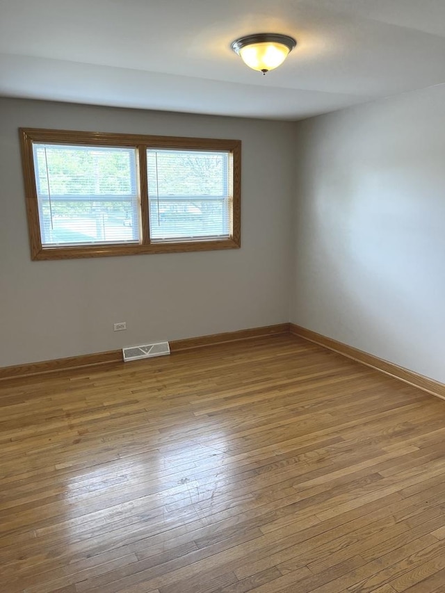 unfurnished room featuring plenty of natural light, hardwood / wood-style flooring, and baseboards