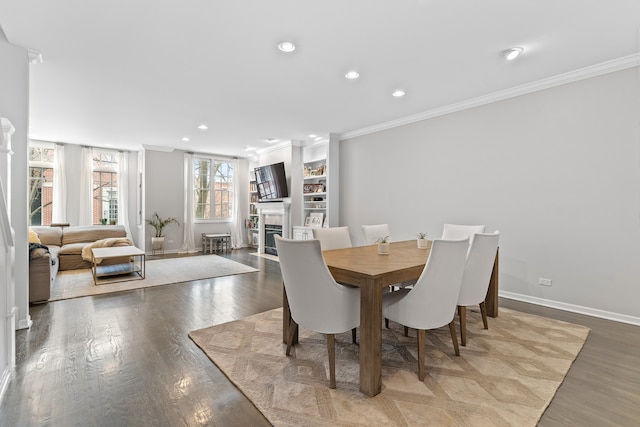 dining room with crown molding, recessed lighting, a glass covered fireplace, wood finished floors, and baseboards