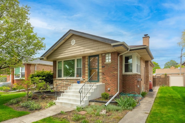 bungalow featuring a chimney and brick siding