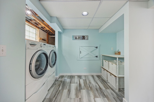 laundry area featuring washer and clothes dryer, baseboards, and wood finished floors