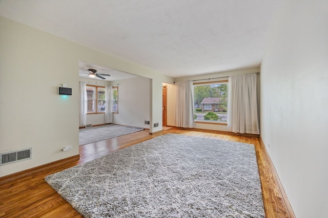 spare room with wood finished floors, a ceiling fan, and baseboards
