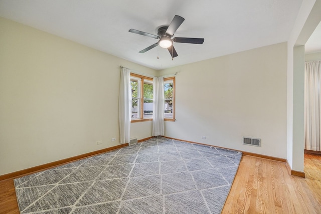 spare room featuring ceiling fan, baseboards, and wood finished floors