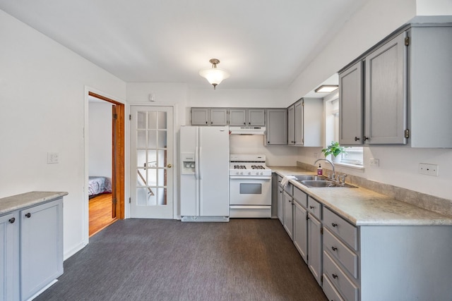 kitchen featuring white appliances, gray cabinets, a sink, under cabinet range hood, and light countertops
