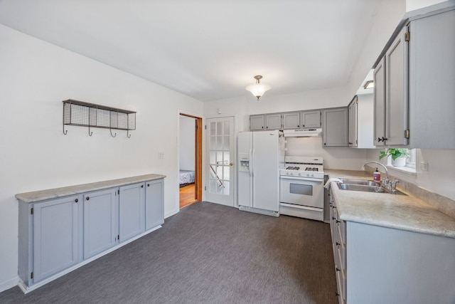 kitchen featuring white appliances, under cabinet range hood, a sink, gray cabinetry, and light countertops