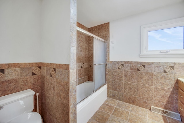 32381 N Forest Dr, Grayslake, IL 60030 - full bathroom with tile walls, shower / bath combination with glass door, vanity, toilet, and a wainscoted wall
