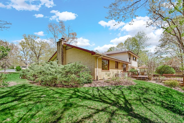 32381 N Forest Dr, Grayslake, IL 60030 - view of home's exterior with brick siding, a chimney, a yard, and a deck