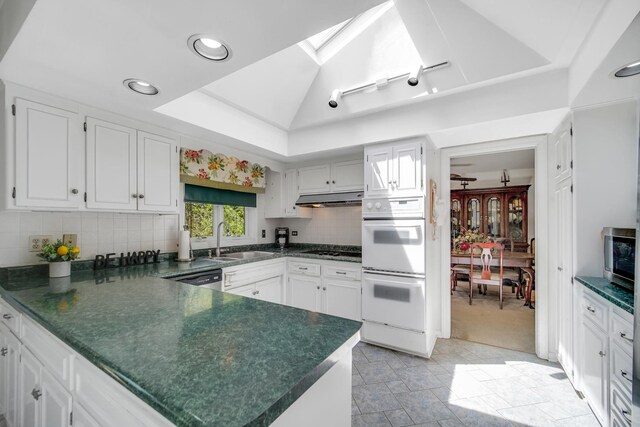 32381 N Forest Dr, Grayslake, IL 60030 - kitchen with white double oven, dark countertops, under cabinet range hood, a peninsula, and white cabinets