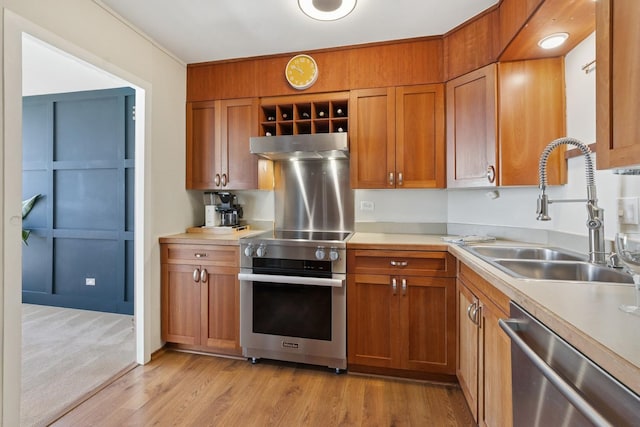 kitchen with stainless steel appliances, range hood, brown cabinetry, a sink, and light countertops