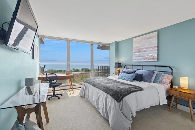 bedroom with an office area, a baseboard heating unit, carpet flooring, and expansive windows