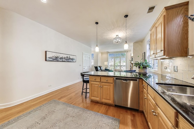 kitchen with dishwasher, light wood-style flooring, a peninsula, and baseboards