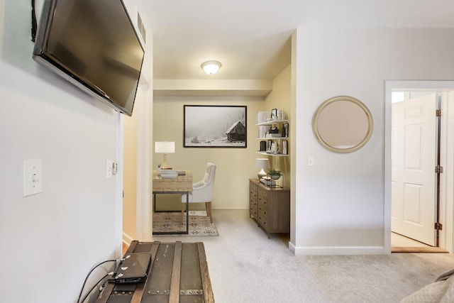 hallway with an office area, carpet, and baseboards