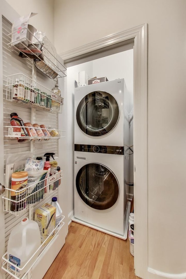 laundry area with stacked washer / dryer and wood finished floors
