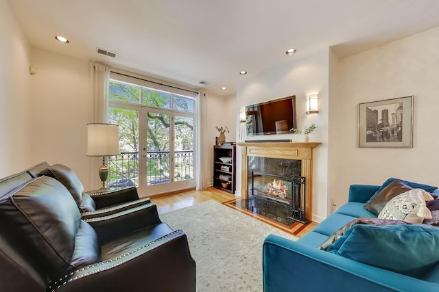 living room with a premium fireplace, wood finished floors, and recessed lighting