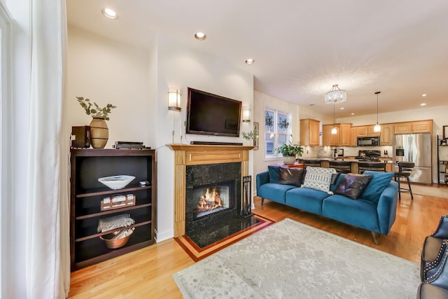 living area featuring light wood finished floors, a high end fireplace, and recessed lighting