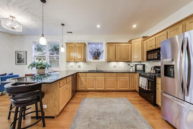 kitchen featuring black appliances, a peninsula, a breakfast bar area, light brown cabinetry, and recessed lighting