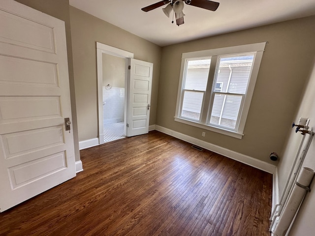 1527 7th St, Peru, IL 61354 - unfurnished bedroom with baseboards, dark wood-style flooring, ensuite bathroom, and a ceiling fan