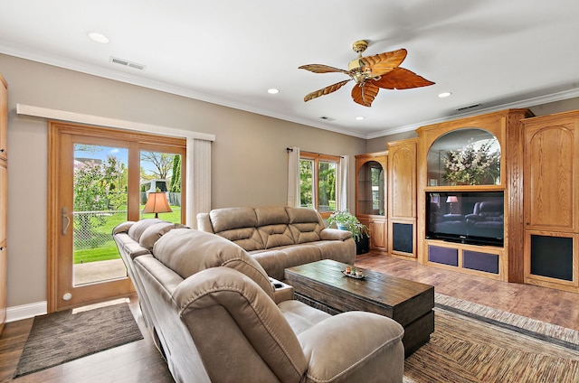 living area with healthy amount of natural light, wood finished floors, ornamental molding, a ceiling fan, and recessed lighting