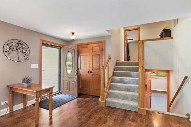 foyer entrance with dark wood finished floors, baseboards, stairs, and healthy amount of natural light