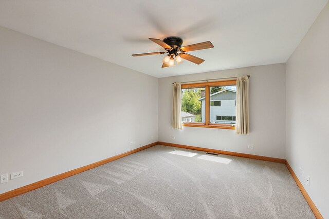 carpeted empty room featuring baseboards and ceiling fan