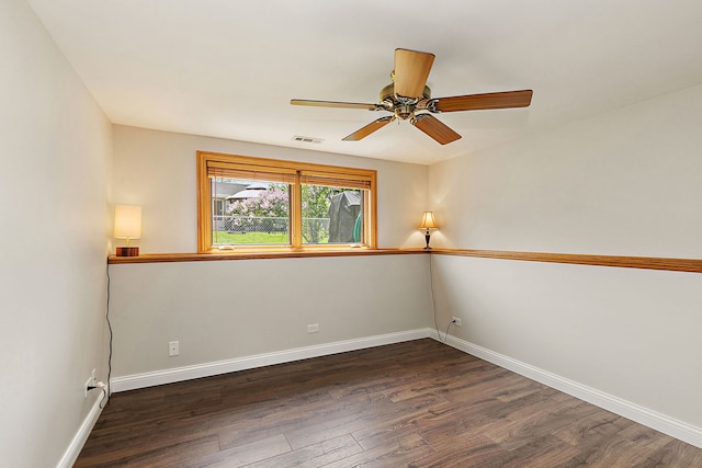 unfurnished room with dark wood-type flooring, a ceiling fan, and baseboards
