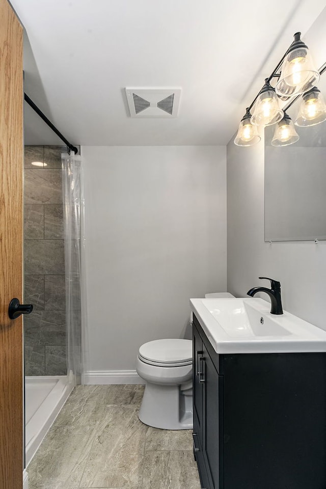 bathroom featuring a stall shower, toilet, vanity, and baseboards