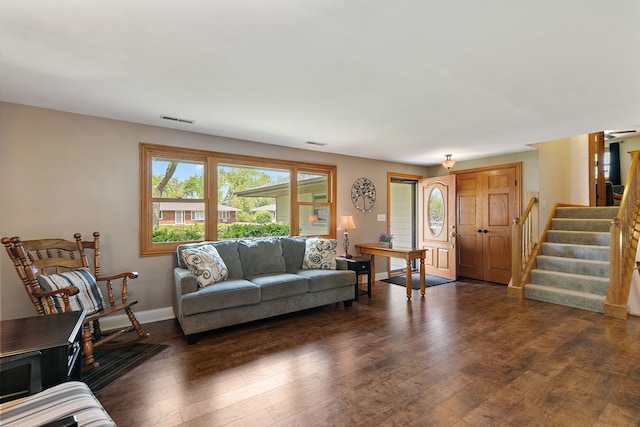 living area featuring dark wood-type flooring, stairway, and baseboards