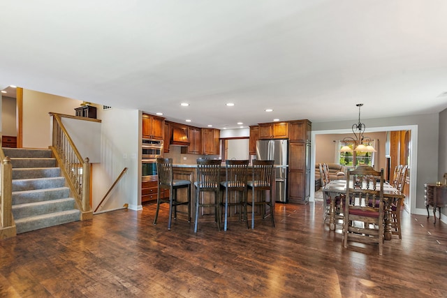 kitchen with appliances with stainless steel finishes, recessed lighting, custom exhaust hood, dark wood-style floors, and a breakfast bar