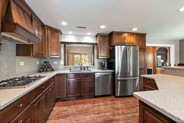 kitchen featuring appliances with stainless steel finishes, a sink, premium range hood, dark wood-style flooring, and recessed lighting