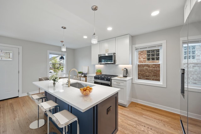 3946 N Oleander Ave, Chicago, IL 60634 - kitchen with stainless steel appliances, a sink, a kitchen island with sink, a breakfast bar area, and light wood-type flooring