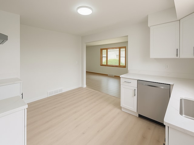 112 Burton Ave, Waukegan, IL 60085 - kitchen featuring stainless steel dishwasher, light wood-style floors, light countertops, and white cabinetry