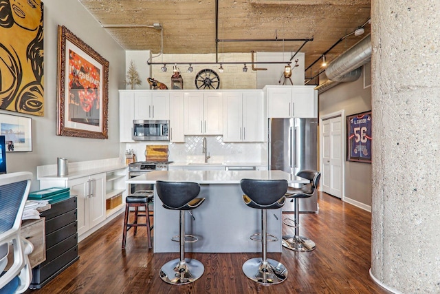 kitchen featuring stainless steel appliances, a sink, track lighting, white cabinetry, and a high ceiling