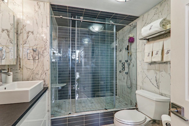 full bathroom with tile walls, toilet, a stall shower, and vanity