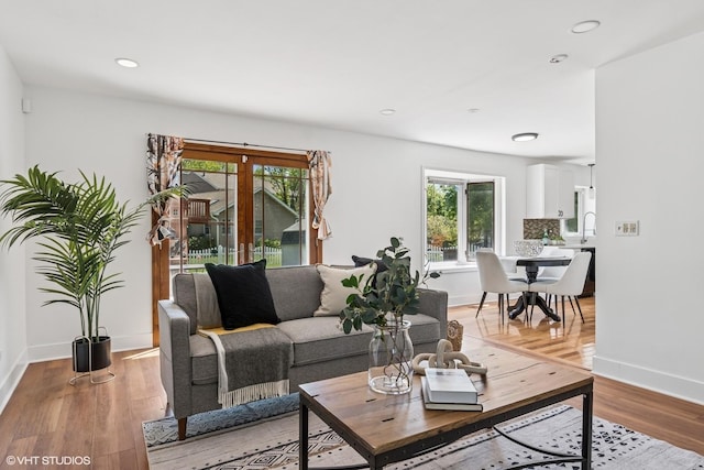 living area with plenty of natural light, baseboards, light wood finished floors, and recessed lighting