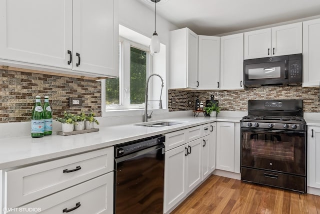 kitchen with black appliances, a sink, white cabinetry, and light countertops