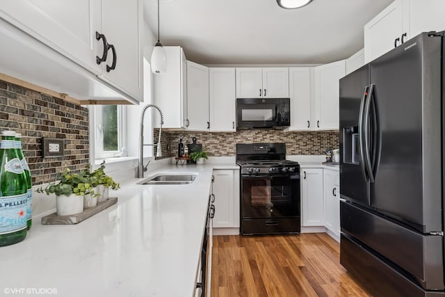 kitchen with black appliances, a sink, light countertops, white cabinetry, and backsplash