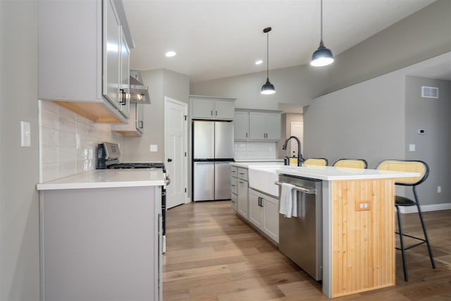 1172 Hershey Rd, Normal, IL 61761 - kitchen featuring appliances with stainless steel finishes, a breakfast bar, a sink, backsplash, and vaulted ceiling