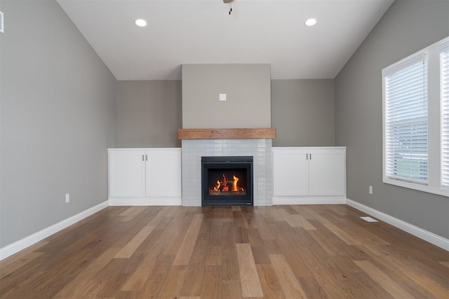 1172 Hershey Rd, Normal, IL 61761 - unfurnished living room with a tiled fireplace, wood finished floors, baseboards, and recessed lighting