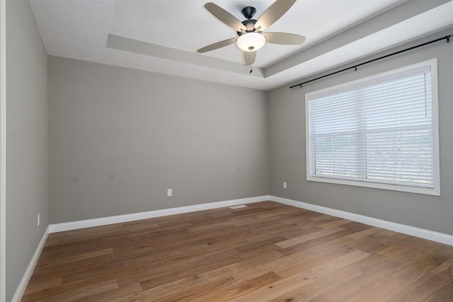 1172 Hershey Rd, Normal, IL 61761 - spare room featuring a ceiling fan, wood finished floors, a tray ceiling, and baseboards