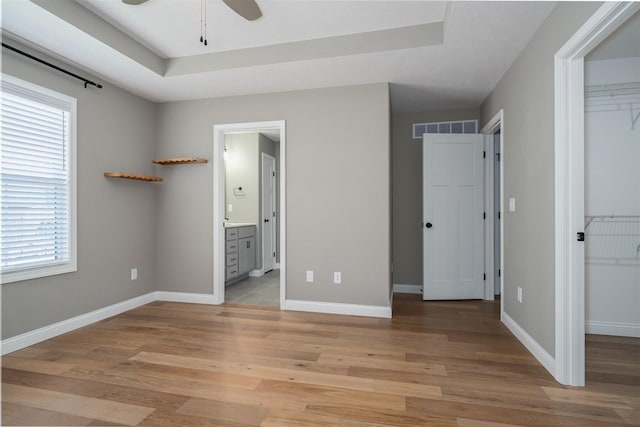 1172 Hershey Rd, Normal, IL 61761 - unfurnished bedroom featuring light wood-style floors, a closet, baseboards, a tray ceiling, and connected bathroom