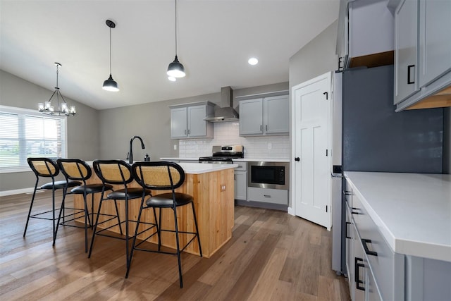 1172 Hershey Rd, Normal, IL 61761 - kitchen with wall chimney exhaust hood, stainless steel appliances, gray cabinets, wood finished floors, and vaulted ceiling