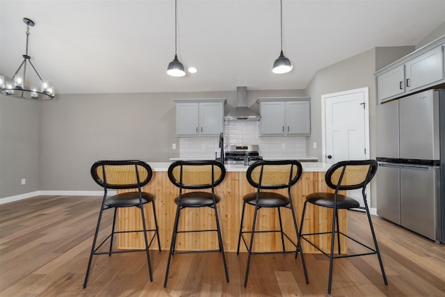 1172 Hershey Rd, Normal, IL 61761 - kitchen featuring appliances with stainless steel finishes, wall chimney exhaust hood, tasteful backsplash, light countertops, and light wood-style flooring