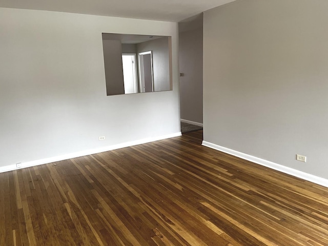 spare room featuring baseboards and dark wood-style flooring