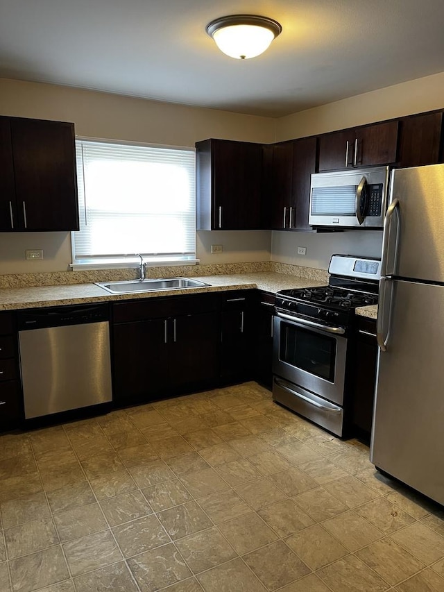 kitchen with appliances with stainless steel finishes, a sink, and dark brown cabinetry