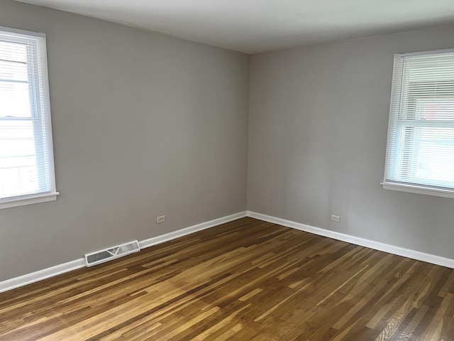 empty room featuring dark wood finished floors, plenty of natural light, and baseboards