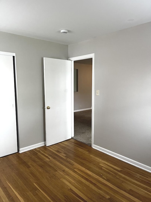 unfurnished bedroom featuring wood finished floors, baseboards, and a closet