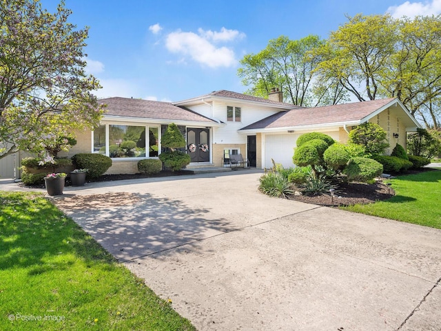 7102 Walden Ln, Darien, IL 60561 - split level home with concrete driveway, a chimney, an attached garage, a front lawn, and brick siding