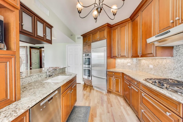 25 E Superior St Unit 2501, Chicago, IL 60611 - kitchen featuring stainless steel appliances, a sink, under cabinet range hood, light wood-style floors, and brown cabinets